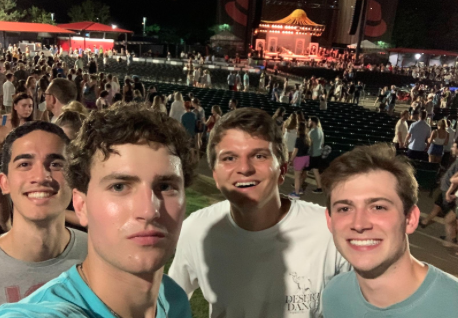 4 students outside at a concert at night